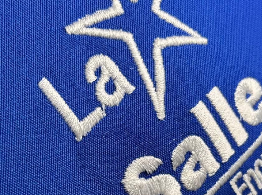 Logo bordado en polo azul – Salto Producciones